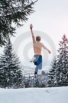 Happy man fell freedom jumping in the air in winter mountains