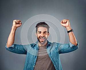 Happy man, fist and celebration for winning, achievement or success against a grey studio background. Excited portrait