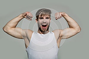 Happy man flex muscles, biceps, triceps on grey background