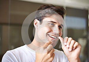 Happy man, flossing and teeth with dental care for hygiene, grooming or freshness in bathroom at home. Face of handsome