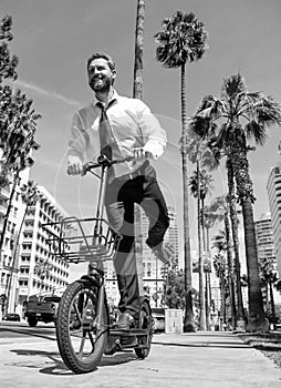 Happy man in formalwear ride e-scooter on sidewalk, e-scooting
