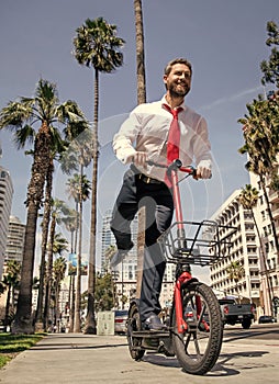 Happy man in formalwear ride e-scooter on sidewalk, e-scooting photo