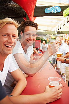 Happy man, friends and drinking at music festival, bar or event for summer party or DJ concert. Portrait of male person