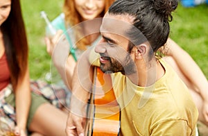 Happy man with friends playing guitar at camping