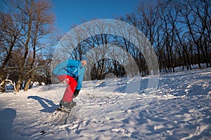 Happy man with funny face is snowboarding in the woods