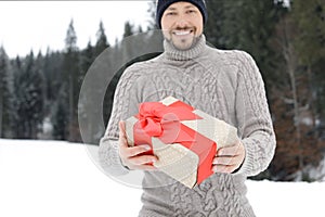 Happy man with gift box outdoors. Winter