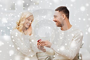 Happy man giving engagement ring to woman at home