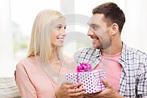 Happy man giving woman gift box at home
