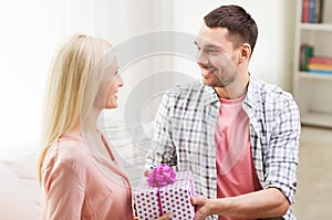 Happy man giving woman gift box at home