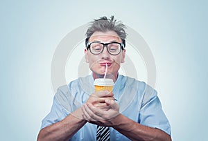 Happy man in glasses drinking from a paper cup with a straw, eyes closed with pleasure