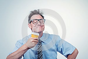 Happy man in glasses drinking from a paper cup with a straw, eyes closed with pleasure