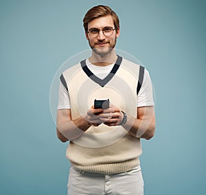 Happy man in glasses typing sms on blue background.