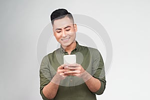 Happy man in glasses typing sms on gray background