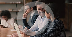 Happy man in glasses working on computer with indian colleague.