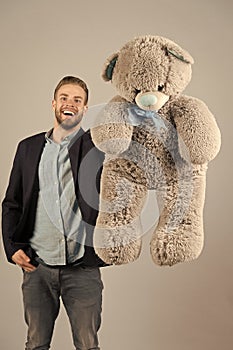 Happy man with grey teddy bear. Macho smile with big animal toy. Gift and present concept. Fashion and style. Birthday photo