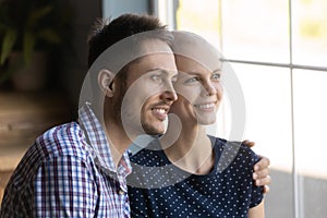 Happy man and hairless ill woman looking out of window