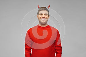Happy man in halloween costume of devil over grey