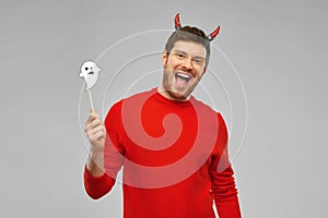 Happy man in halloween costume of devil over grey