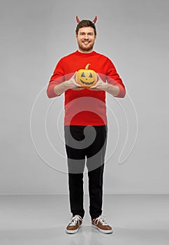 Happy man in halloween costume of devil over grey