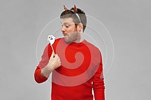 Happy man in halloween costume of devil over grey