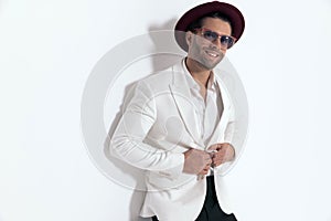 happy man with hat and sunglasses unbuttoning white jacket suit