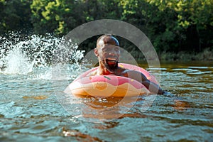 Happy man having fun, laughting and swimming in river