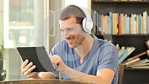 Happy man with headphones watching media on tablet