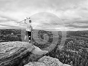 Happy man hiker holding medicine crutch above head, injured knee fixed in knee brace feature