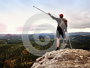 Happy man hiker holding medicine crutch above head, injured knee fixed in knee brace feature