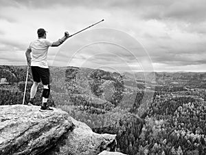 Happy man hiker holding medicine crutch above head, injured knee fixed in knee brace feature