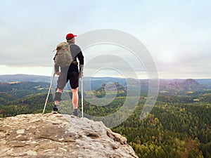 Happy man hiker holding medicine crutch above head, injured knee fixed in knee brace feature