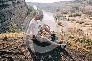 Happy Man hiker sitting at mountain top and looking at scenic landscape