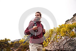 Happy, man and hiking with backpack on mountain for travel, adventure and fitness. Male person, smile and tourist