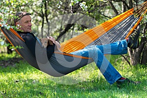 Happy man with his funny dog relaxes in a hammock