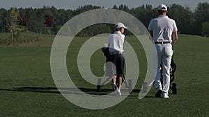 Happy man with his son golfers walking on perfect golf course at summer day