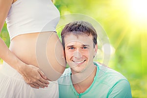 Happy man holding belly of pregnant woman