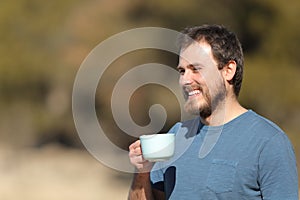 Happy man holding coffee cup contemplating views in nature