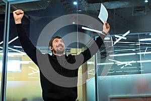 Happy man holding documents, rejoices at a successful deal or good news on work. Emotion of joy, business victory success.