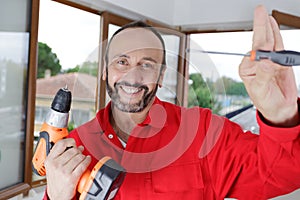 Happy man holding drill and screwdriver