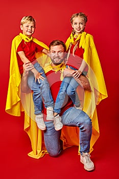 Happy man holding super kids on shoulders posing at camera