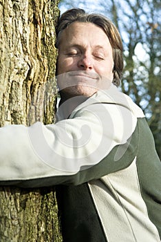 Happy man hugging tree
