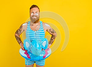 Happy man with inflatable donut with elephant is ready to swim