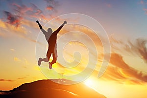 Šťastný muž skákanie radosť na vrchol z hora na západ slnka. úspech 