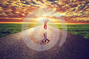 Happy man jumping on long straight road, way towards sunset sun