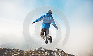 Happy Man jumping on mountains cliff to clouds sky