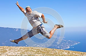 Happy man jumping over mountains, sky and sea