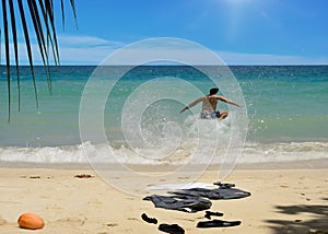 Happy man jumping into sea. Business suit on beach