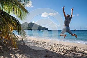 Happy man jumping up on the beach to celebrates summer holidays