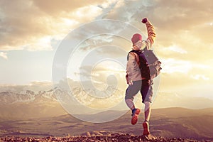 Happy man jumps in winner pose against sunset mountains