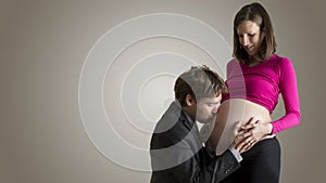 Happy man kissing the belly of his pregnant wife